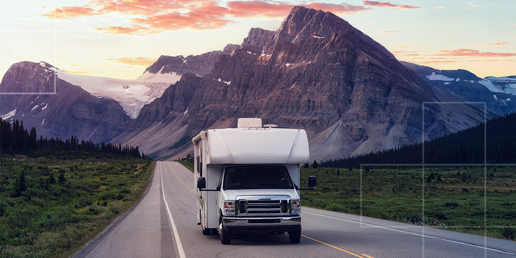 Un camping-car sur une route de montagne durant le coucher de soleil.